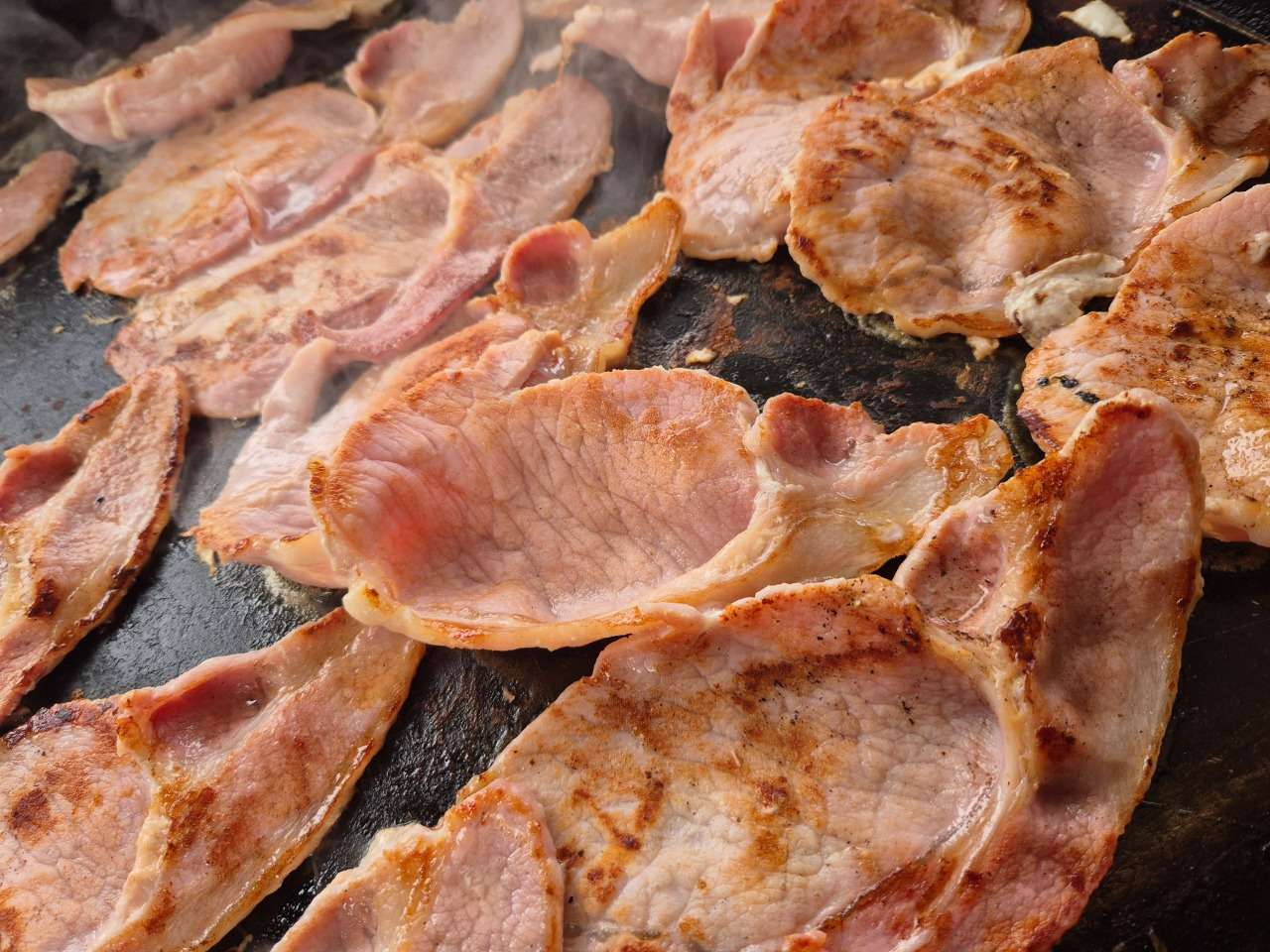 Fresh bacon cooking on the grill